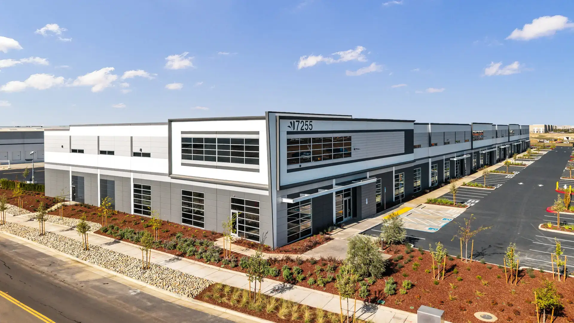 Aerial commercial real estate photo of a new industrial warehouse near the Sacramento Airport featuring modern architecture, landscaped frontage, and ample parking.